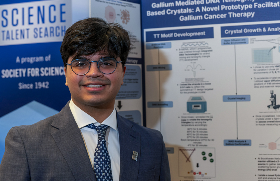 teen researcher stands in front of his project at science competition 