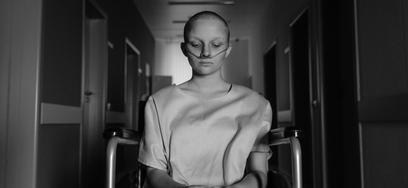 Cancer patient sitting in hospital hallway with dark lighting