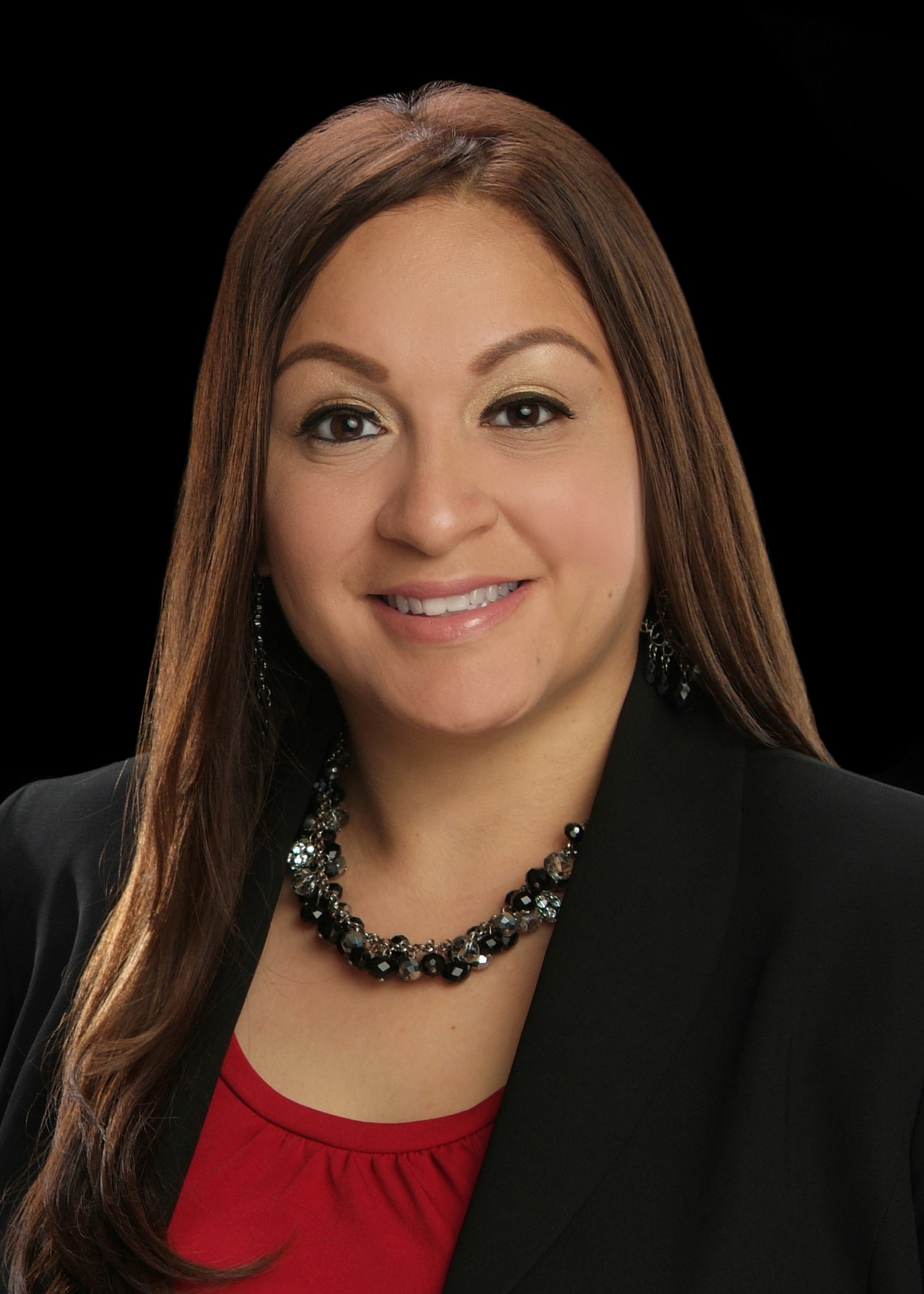 Young hispanic woman with long brown hair in a red top and black jacket wearing a necklace and earrings