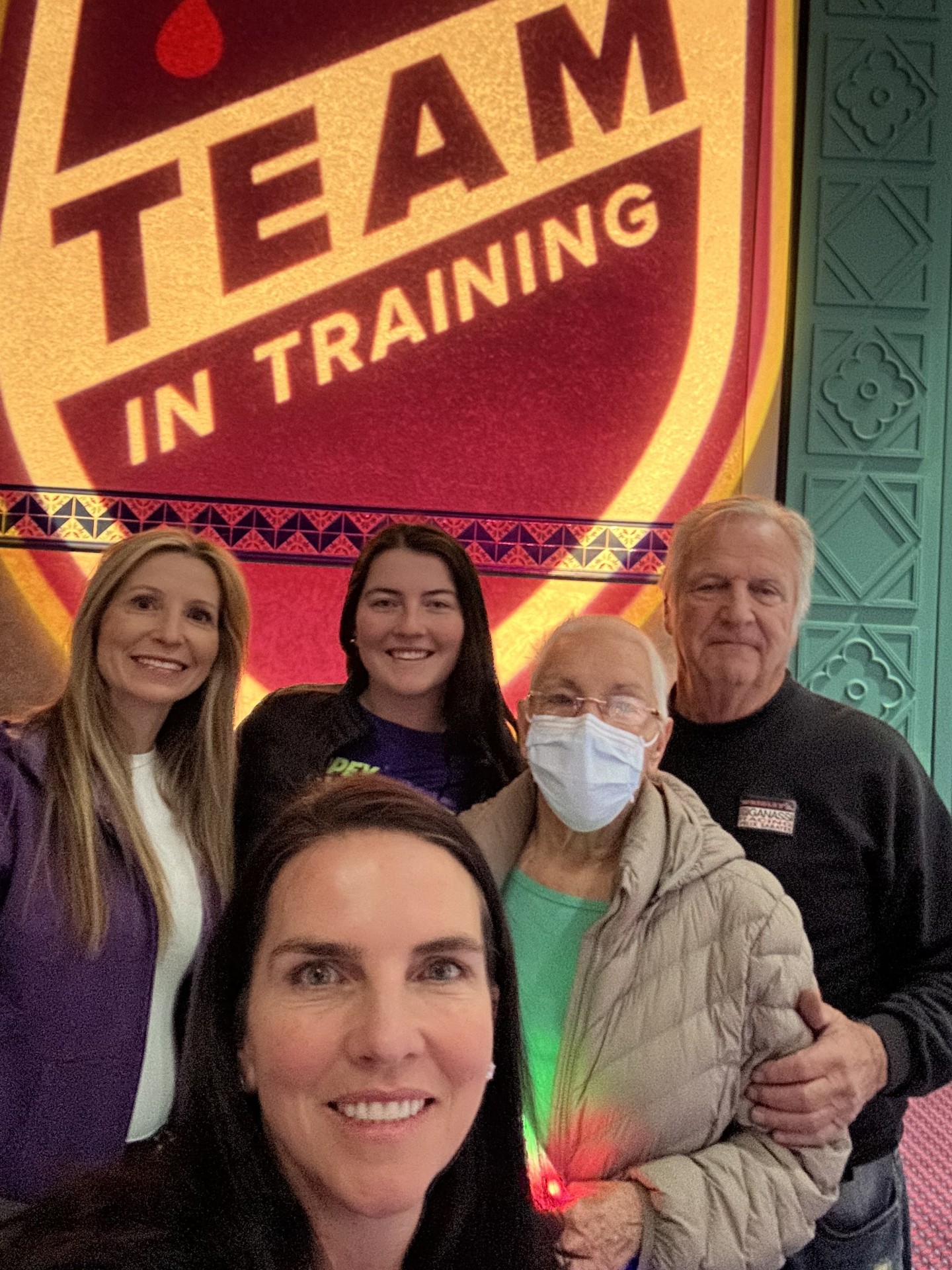 Alexis family of five with grandmother wearing glasses and a mask standing in front of TNT photo