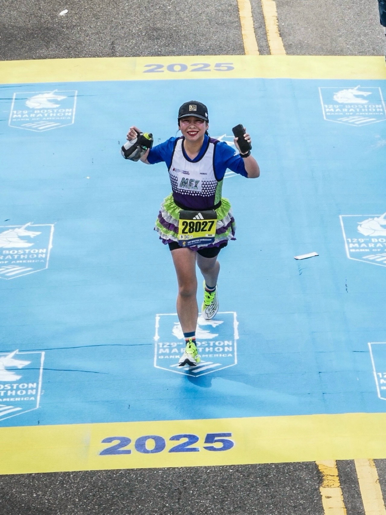 Teammate running across the Boston Marathon finish line to achieve the world majors and team in training jersey