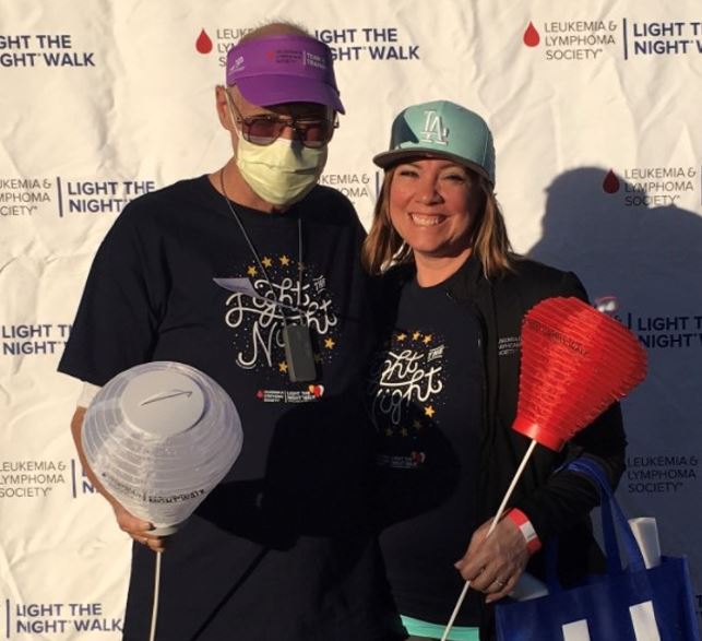 father with AML and daughter standing outside with light the night with hat team in training logos and red and white lanterns