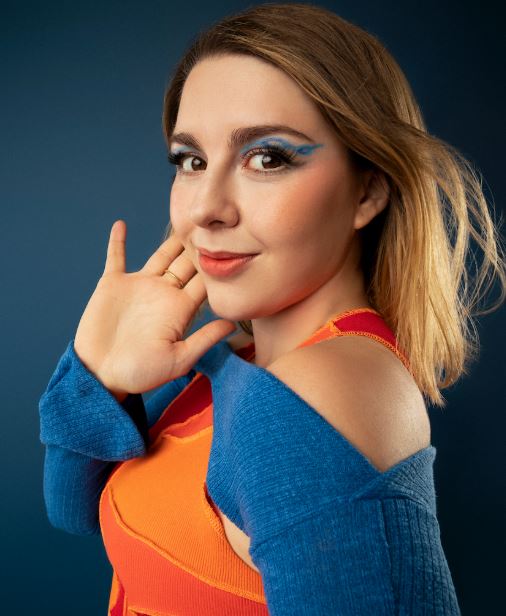 young adult leukemia survivor with vivid makeup and colorful clothes with closed mouth smile