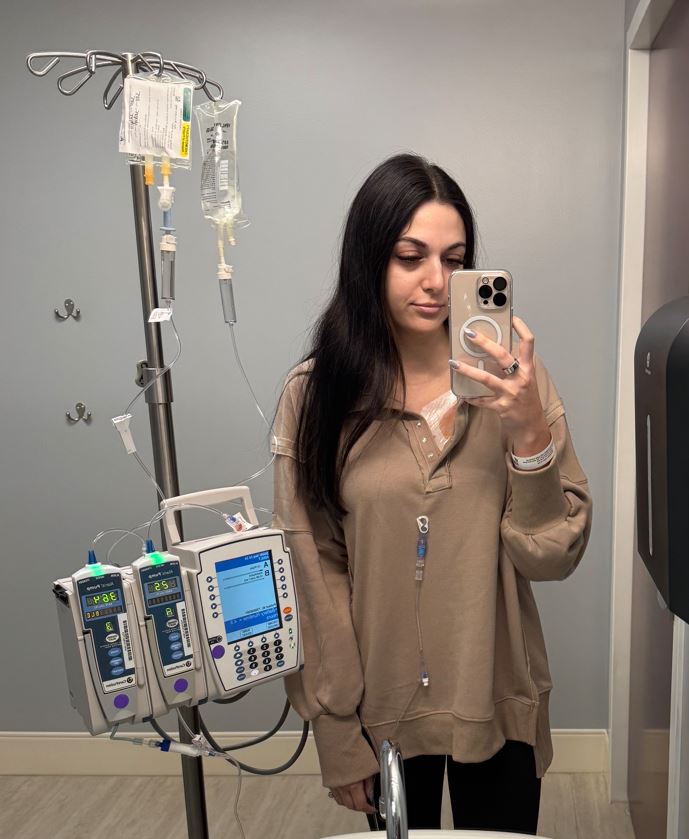 young adult patient lymphoma standing with IV pole in front of a mirror selfie
