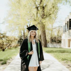 Young blond woman in a cap and gown, green stole and platform shoes