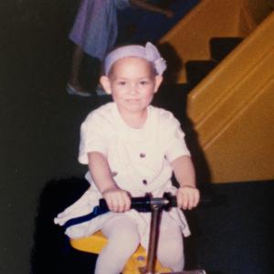 Little girl with leukemia on a scooter with a purple ribbon headband