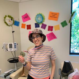 Young woman with glasses wearing a floral bucket hat holding a medal in her hand striped shirt and sweatpants