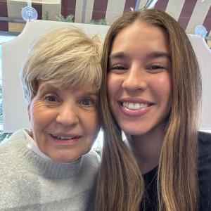 older woman with short blond hair in a sweater next to younger woman with long brown hair and a black shirt