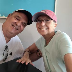 older white couple he has on a ball cap and white t-shirt and she has on pink ball cap and glasses and a white t-shirt
