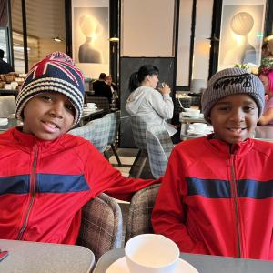 two young black boys wearing knitted hats and matching red and blue jackets