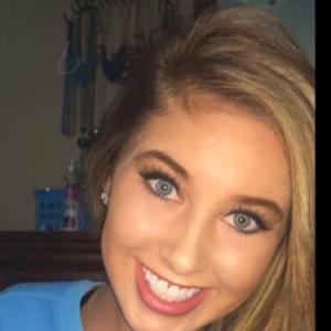 young white woman with long blond hair and blue eyes smiling and wearing a light blue tshirt
