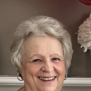 older white woman with short white hair wearing silver hoop earrings and a black and white polka dot blouse