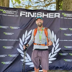 Athletic blood cancer survivor standing with finisher and baseball cap