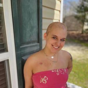 young adult blood cancer survivor with a pink wrap dress and port scar smiling nodular sclerosis Hodgkin lymphoma (NSHL)