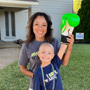 Peyton young hispanic mom in a gray tshirt with her bald son wearing bright green boxing gloves and an I Am a Warrior tshirt