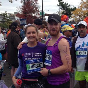 young white woman in a TNT shirt and race number and a sequined skirt with survivor written on her leg standing next to young white man with a black Nike hat beard and mustache