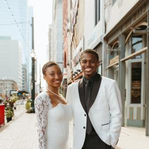 Jayson young black couple in wedding attire white coat black shirt and tie standing outside in a downtown area