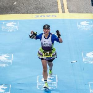 Teammate running across the Boston Marathon finish line to achieve the world majors and team in training jersey
