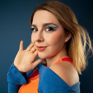young adult leukemia survivor with vivid makeup and colorful clothes with closed mouth smile