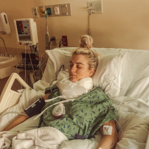 Brescia young white woman laying in a hospital bed with blond hair pulled into a pony tail on top of her head eyes closed wearing green leaf hospital gown