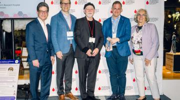 Five individuals pose for a photo in front of an Leukemia & Lymphoma Society backdrop.