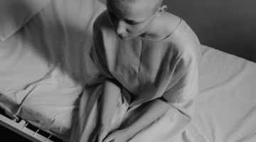 Cancer patient sitting on hospital bed with dark lighting