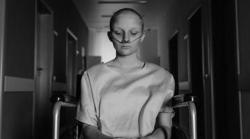 Cancer patient sitting in hospital hallway with dark lighting