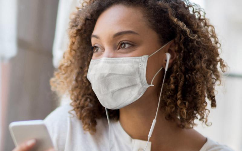 image of woman wearing a face covering while on a phone