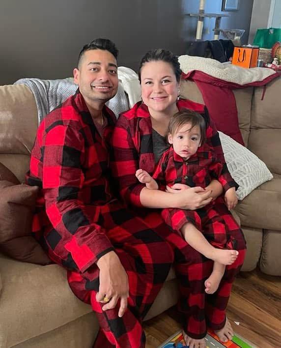 Abby, her husband, and her son all smile into the camera wearing matching red flannel pajamas.