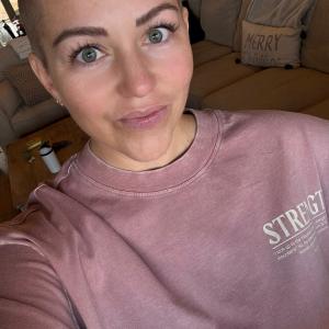 Young woman with bald head in purple sweatshirt diffuse large B-cell non-Hodgkin lymphoma (DLBCL)