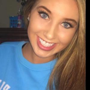 young white woman with long blond hair and blue eyes smiling and wearing a light blue tshirt