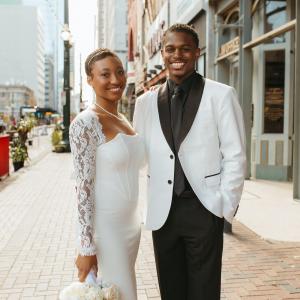 Jayson young black couple in wedding attire white coat black shirt and tie standing outside in a downtown area