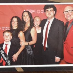 Julie white family in front of Visionary of the Year signage with little boy wearing an honored hero sash