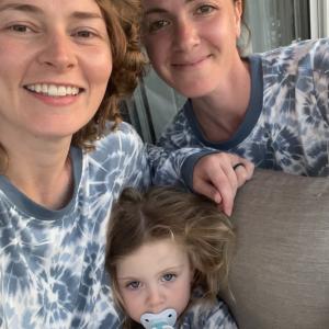 Kimbery two young white women and a little girl all wearing blue tie-dye shirts sitting on a brown sofa
