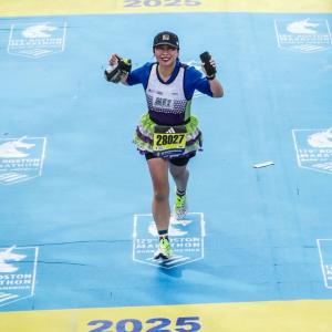 Teammate running across the Boston Marathon finish line to achieve the world majors and team in training jersey