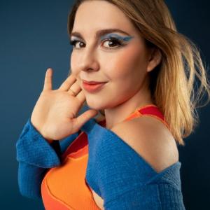 young adult leukemia survivor with vivid makeup and colorful clothes with closed mouth smile