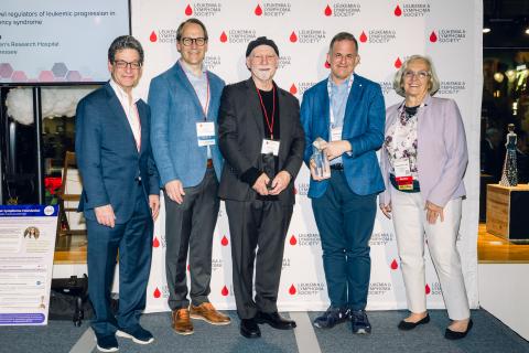 Five individuals pose for a photo in front of a Leukemia & Lymphoma Society backdrop