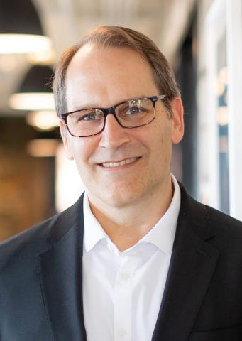 Man with glasses in white shirt and navy jacket
