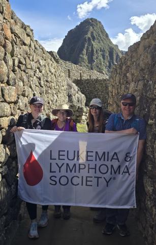 A group of trekkers at Machu Picchu hold an LLS banner
