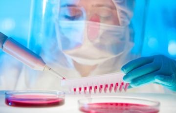 Scientist in face mask and shield sampling blood