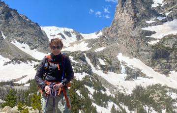 Alice, myeloma survivor, on a hiking trip, standing in front of mountains