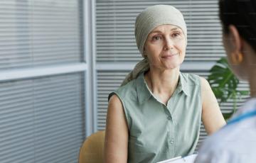 A woman with a bandana sits across from another person behind a desk