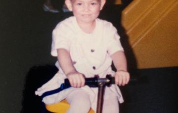 Little girl with leukemia on a scooter with a purple ribbon headband