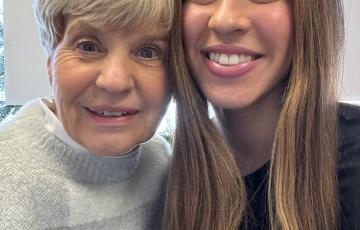 older woman with short blond hair in a sweater next to younger woman with long brown hair and a black shirt