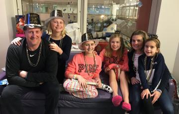 white family with New Year's Eve hats on including bald girl with a pink shirt on