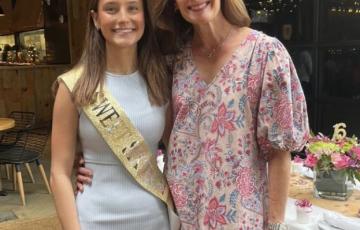 young white woman wearing sweet sixteen sash and white dress with cowboy boots and her mother in a floral dress and sneakers