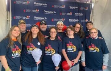 group of 10 white people various ages wearing Light The Night tshirts two holding white balloons three holding red balloons