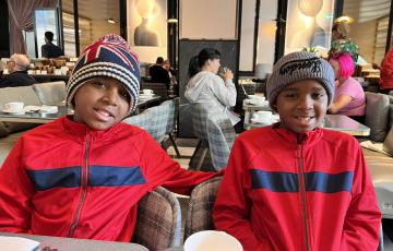 two young black boys wearing knitted hats and matching red and blue jackets