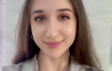 young hispanic woman with large green eyes an pink lipstick wearing a grayish blouse