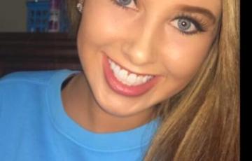young white woman with long blond hair and blue eyes smiling and wearing a light blue tshirt